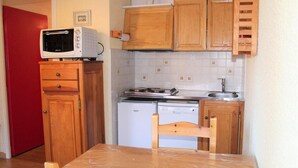 Una cocina compacta con gabinetes de madera, microondas, estufa y lavavajillas.