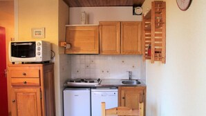 Una cocina compacta con muebles de madera, microondas integrado, estufa y lavavajillas.