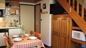 Une cuisine compacte avec des meubles en bois, un four à micro-ondes et une table à manger pour quatre personnes.