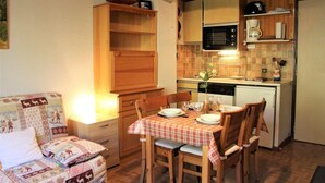 Une cuisine compacte avec des meubles en bois, un four à micro-ondes et une machine à café. On y trouve une table à manger, mise avec des assiettes et des verres.