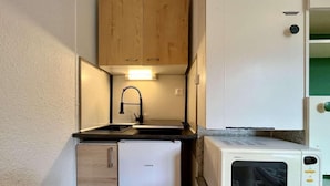 A compact kitchenette with a refrigerator, a microwave, a sink, and wooden cabinets. - 100m from ski slopes, 3rd floor, tv, 18m², Vars (Vars)