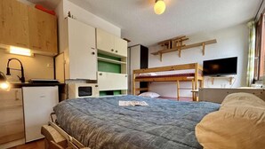 A compact room with a bunk bed, a small kitchenette, and a single bed with a blanket. - 100m from ski slopes, 3rd floor, tv, 18m², Vars (Vars)