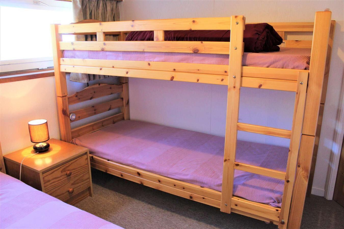 A bunk bed with a bedside table and lamp.