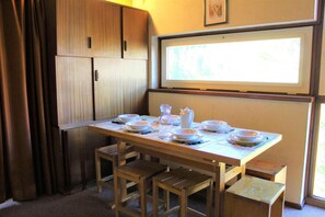 Un coin repas avec une table en bois mise pour quatre personnes, comprenant des assiettes, des bols et un pichet.