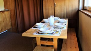 A wooden dining table with plates and a pitcher, set against a wooden cabinet and a window. - 200m from resort center, 2nd floor, balcony, tv, 40m², Vars (Vars)