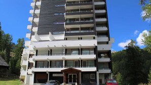 A multi-story building with a modern architectural design, featuring balconies on each floor and a ground-level entrance. - 200m from resort center, 2nd floor, balcony, tv, 40m², Vars (Vars)