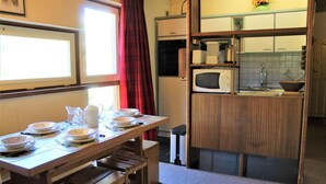 A compact kitchen with a wooden table set for dining, a microwave, and a sink. - 200m from resort center, 2nd floor, balcony, tv, 40m², Vars (Vars)