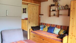 A cozy room with a wooden sofa bed, a small bedside table, and a shelf with books and decorative items. - 200m from resort center, 2nd floor, balcony, tv, 40m², Vars (Vars)
