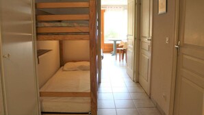 A narrow hallway leading to a room with a bunk bed and a small table and chair set in the background. - 200m from ski slopes, Ground floor, terrace, tv, 42m², Vars (Vars)