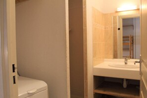 A small bathroom with a white toilet, a sink with a mirror, and beige tiles. - 50m from shops, Ground floor, terrace, tv, 42m², Vars (Vars)