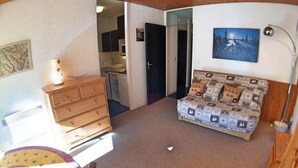 A room with a bed, a dresser, a desk, and a chair. There is a door leading to another room.