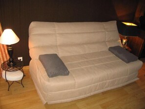 A beige sofa with two grey cushions, a small round table with a lamp, and a wooden floor. - 200m from resort center, 6th floor, balcony, tv, 28m², Vars (Vars)