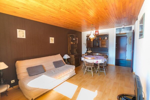 A cozy living room with a wooden ceiling, a sofa, a dining table with chairs, and a kitchen area with cabinets and a hanging light fixture. - 200m from resort center, 6th floor, balcony, tv, 28m², Vars (Vars)
