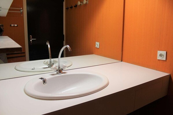 A bathroom with a white sink, a mirror, and an orange wall. - 50m from resort center, 7th floor, view mountain, balcony, parking, tv, 28m², Vars (Vars)