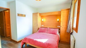 A bedroom with a wooden bed, two bedside lamps, and a wooden wardrobe.
