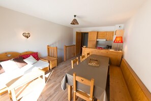 Een kleine kamer met een bed, een eettafel en een kitchenette.