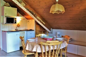 Enjoy meals in this kitchen with a dining area featuring a stove, refrigerator, microwave, and wooden cabinet above the sink.