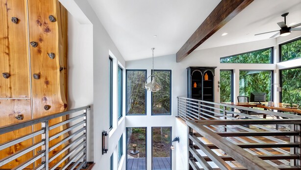 Un interno moderno con scala in legno, ampie finestre e zona pranzo.