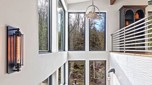 Un interno moderno con ampie finestre, una scala e un lampadario.