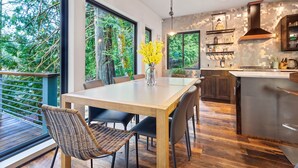 Una cucina moderna con zona pranzo, ampie finestre e vista sugli alberi.
