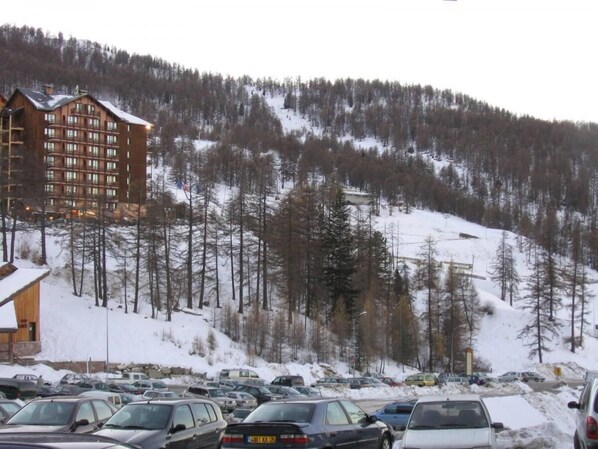 A multi-story lodge with a ski slope in the background.