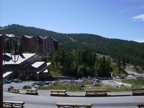 A mountainous area with a parking lot, several buildings with sloped roofs, and picnic tables. - 50m from resort center, balcony, tv, ski locker, 23m², Risoul (Risoul)