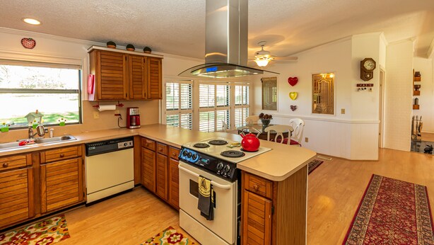 A kitchen with wooden cabinets, a stainless steel range hood, a dishwasher, and a red kettle on the island. - Rural Retreat with Private Pond, ATV Trails and Event Space (Buffalo)