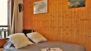 Une pièce aux murs lambrissés, avec un lit, des oreillers, une carte et un livre posés sur le lit.