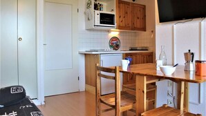 Une cuisine compacte avec des meubles en bois, un four à micro-ondes et une décoration murale sur le thème de la pizza.