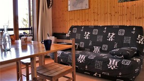 L’intérieur est en bois et comprend un canapé, une table et des chaises. Une carte est accrochée au mur.