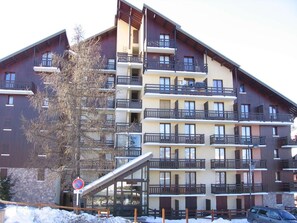 A multi-story hotel with balconies, a ski lift, and a no parking sign.