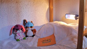 A small, cozy room with a bunk bed and a single bed, featuring a textured wall and a wooden frame. - 50m from ski slopes, 3rd floor, balcony, tv, ski locker, 24m², Risoul (Risoul)