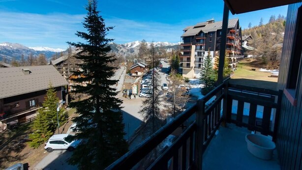 A mountain resort with a view of snow-capped peaks, a parking area, and a building with balconies. - 50m from ski slopes, 3rd floor, balcony, tv, ski locker, 24m², Risoul (Risoul)