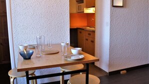 A dining area with a wooden table set for four, including bowls, glasses, and plates. - 50m from ski slopes, 3rd floor, balcony, tv, ski locker, 24m², Risoul (Risoul)
