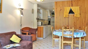 Un espace de vie compact comprenant un canapé, une table à manger et un coin cuisine.