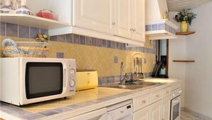 Une cuisine avec des meubles blancs, un four à micro-ondes, un grille-pain et un évier.