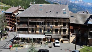 A multi-story hotel with balconies, a parking area, and a mountainous backdrop. - 20m from ski slopes, 3rd floor, balcony, tv, ski locker, 21m², Risoul (Risoul)