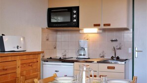 Une cuisine compacte équipée d’un four à micro-ondes, d’un grille-pain, d’une machine à café et d’un lave-vaisselle.