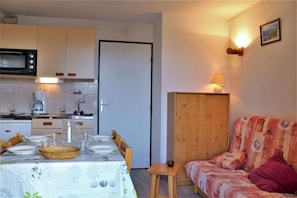 A compact living space with a kitchenette, dining area, and a sofa.