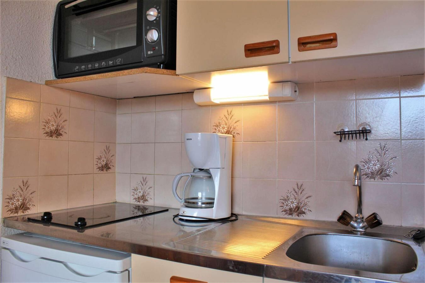 Eine kleine Küche mit Mikrowelle, Kaffeemaschine und Spüle.