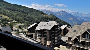 Ein Bergresort mit mehrstöckigen Gebäuden, einer Seilbahn und Blick auf die umliegenden Berge.