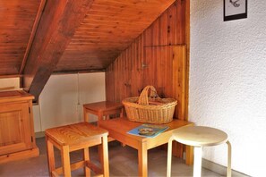Cozy attic retreat with a wooden table, wicker basket, and a single chair.