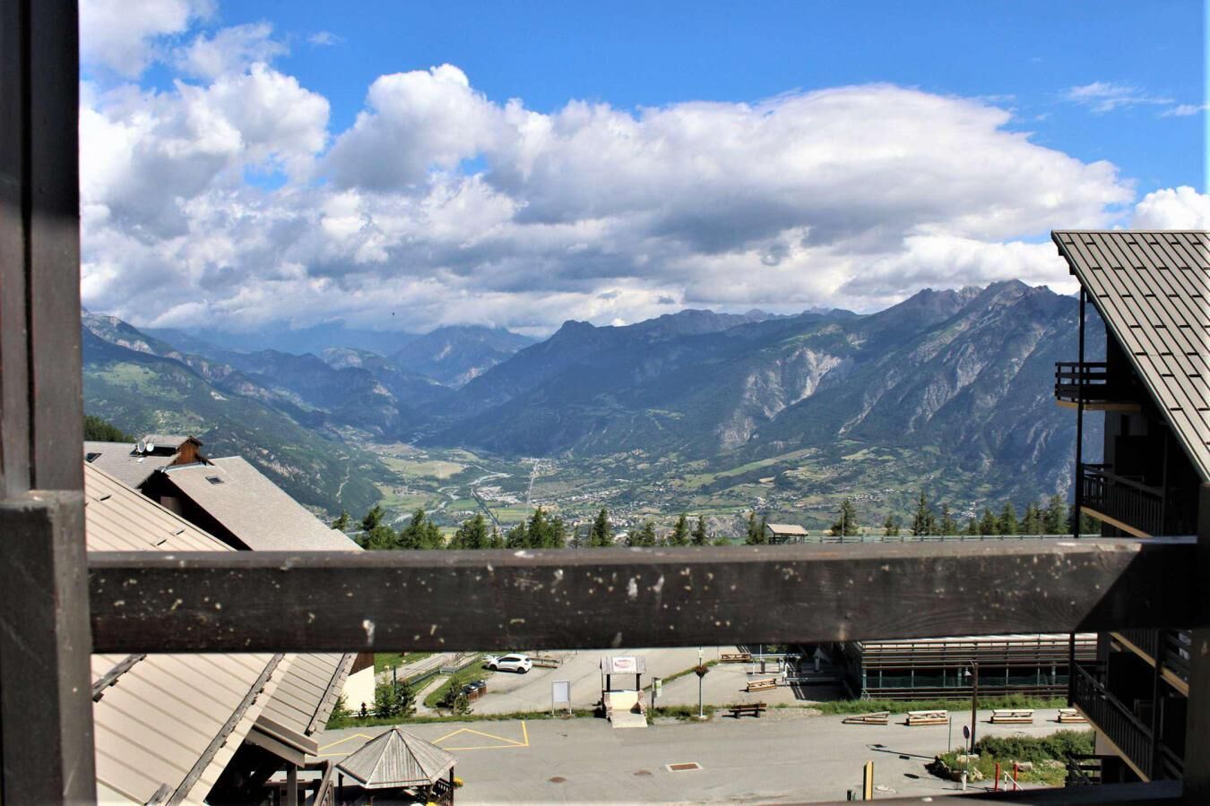 Une vue d’un paysage montagneux, avec un espace de stationnement et des bâtiments au premier plan.