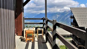 Un balcón con mesa y sillas de madera que da a un paisaje montañoso.