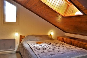 Cozy attic bedroom with a single bed, bedside lamps, and a bench.
