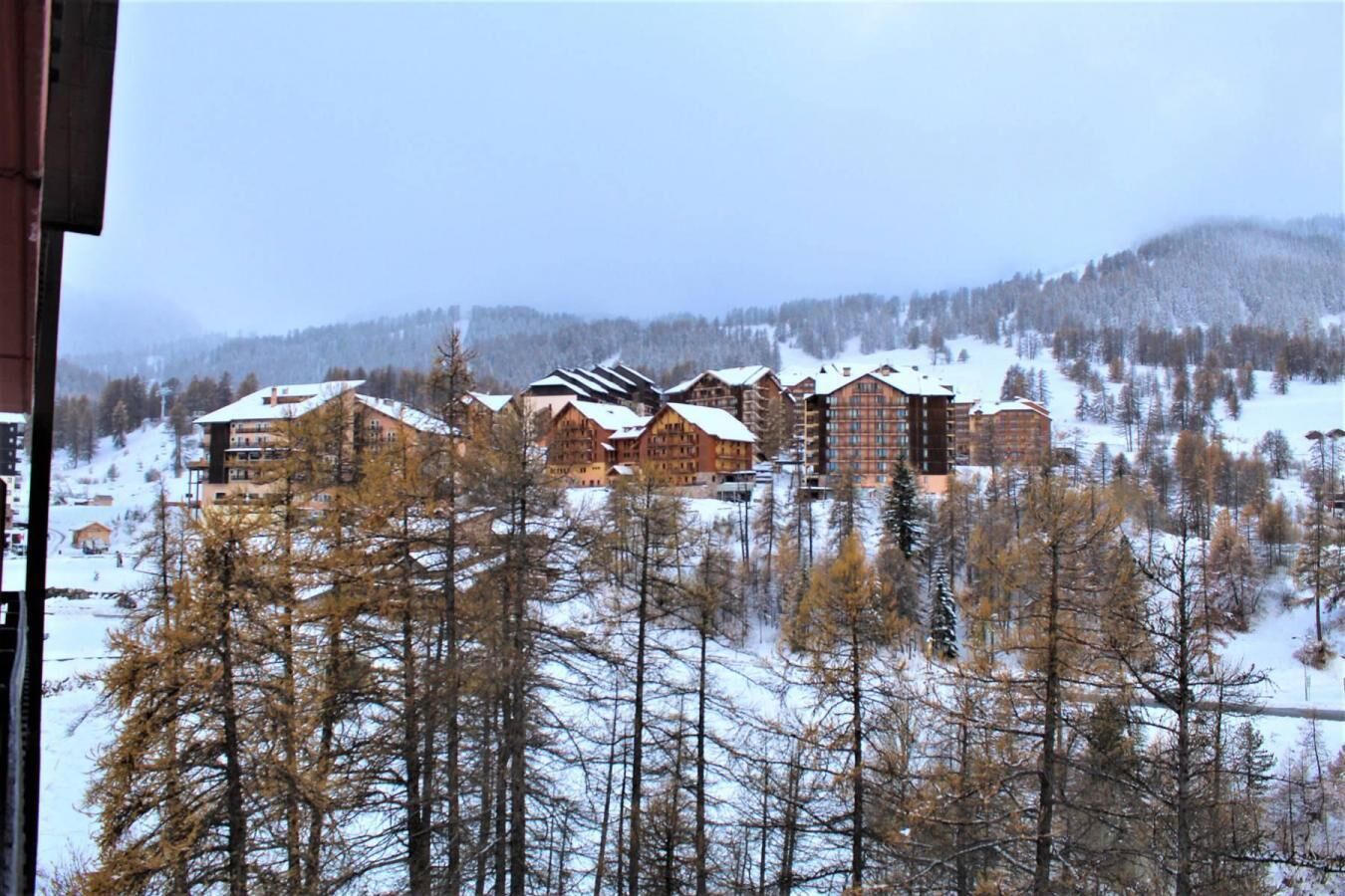 A lodge with multiple buildings, surrounded by snow-covered trees and hills.