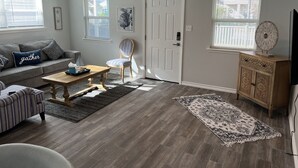 A living room with a gray sofa, striped armchair, wooden coffee table, and a patterned rug. - Lovely 1 Bedroom walking distance from Beach! (Galveston)