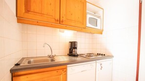A compact kitchen with wooden cabinets, a stainless steel sink, a coffee maker, and a microwave.
