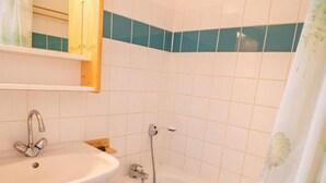 A bathroom with a white sink, mirror, and a bathtub with a showerhead.