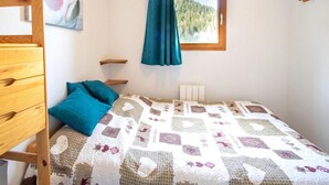 A bedroom with a bed, a wooden dresser, a window with a view of a forest, and a painting on the wall. - 70m from ski slopes, 1st floor, view mountain, parking, tv, ski locker, 46m², Valfréjus (Valfréjus)